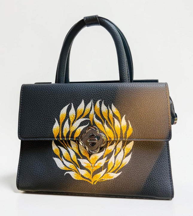 Black handbag with hand painted floral design held by hand from Ekeha