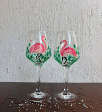 Set of 2 hand-painted wine glasses with pink flamingo design and green leaves on clear glass