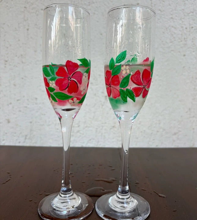 Set of 2 champagne glasses with hand-painted red floral design and green leaves on clear glass